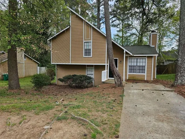a view of a house with a yard and large tree