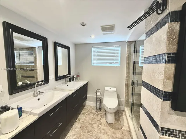 a bathroom with a double vanity sink toilet and mirror
