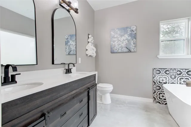 a bathroom with a toilet sink vanity tub and mirror