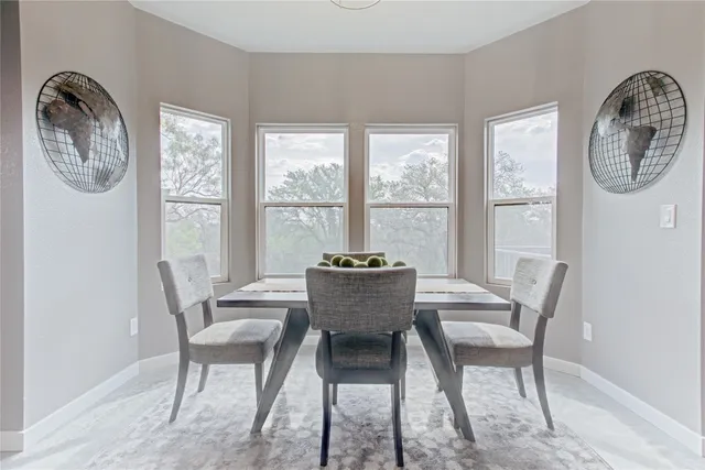 a large room with stainless steel appliances a dining table a microwave a refrigerator and cabinets