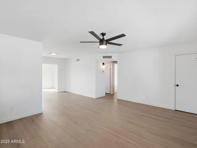 an empty room with wooden floor and ceiling fan