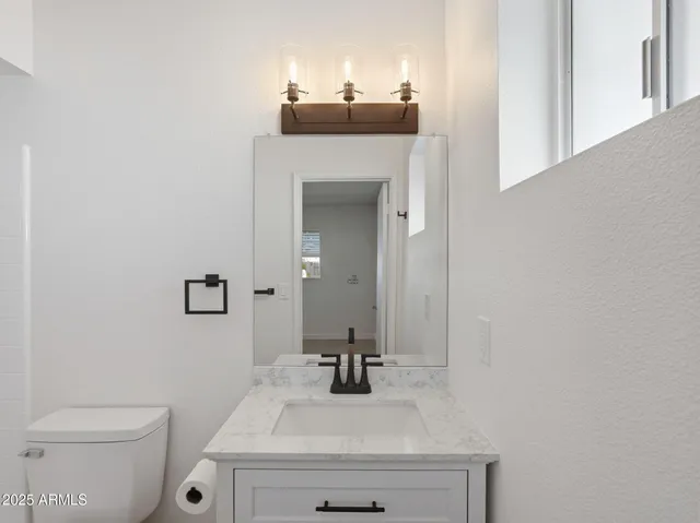 a bathroom with a sink vanity mirror and toilet