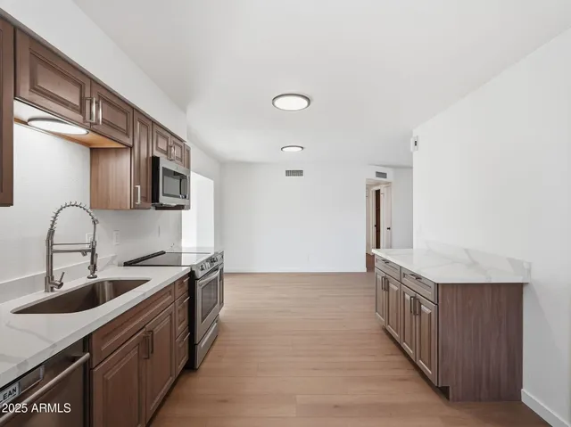 a kitchen with stainless steel appliances granite countertop a sink and a stove with wooden floors