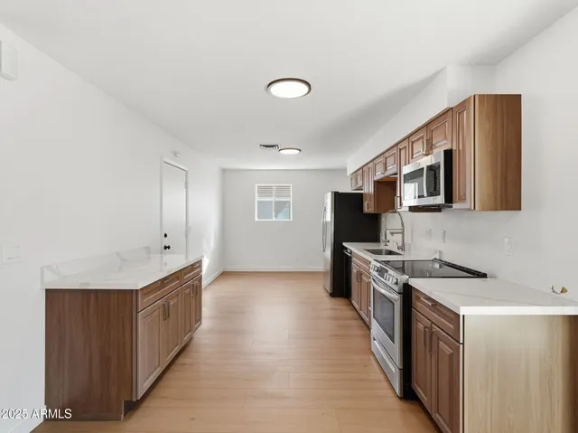 a kitchen with stainless steel appliances granite countertop a stove top oven a sink dishwasher and a refrigerator