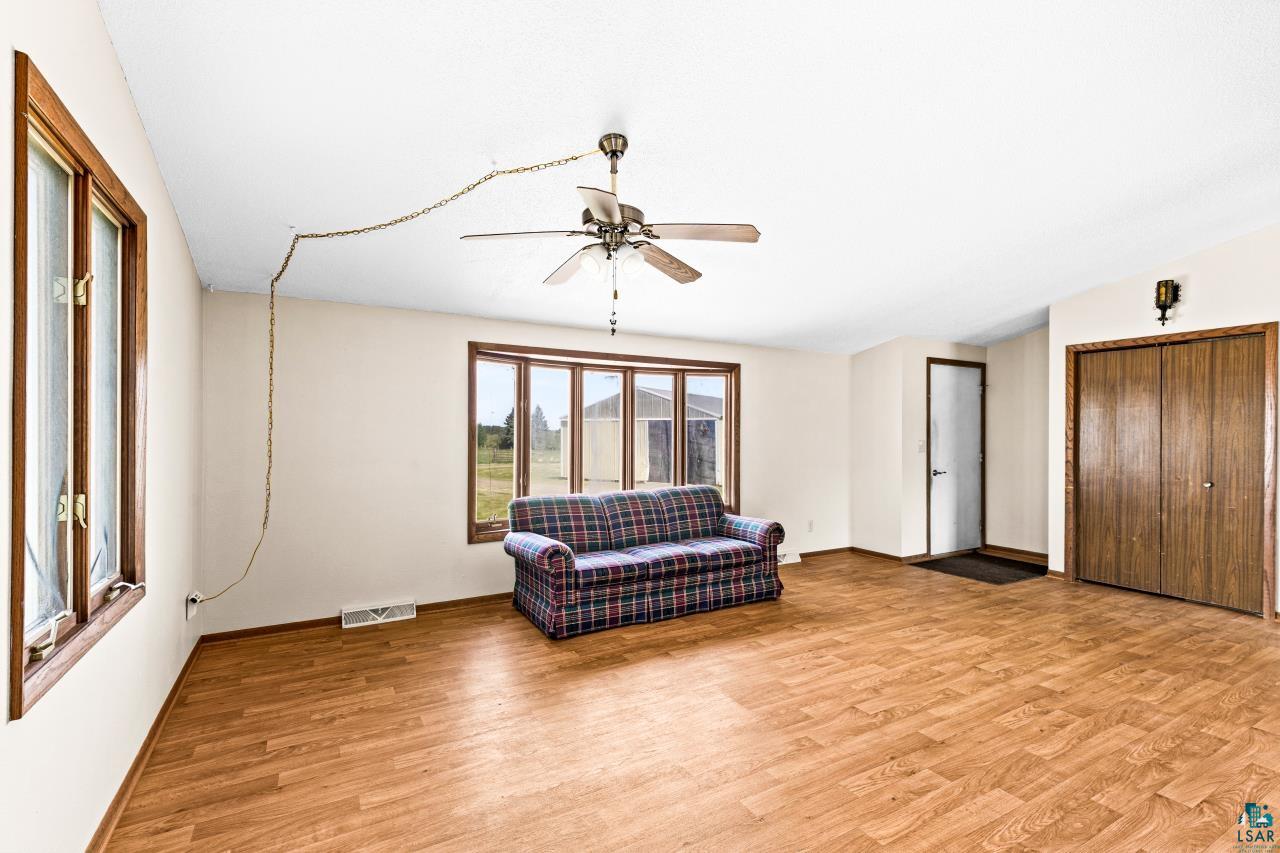 6606 Metso Road Kettle River, MN 55757 - Photo 20 of 84 Bright living area featuring wood-finish flooring, multiple windows with wood trim, a ceiling fan, and a double-door closet with wood panels
