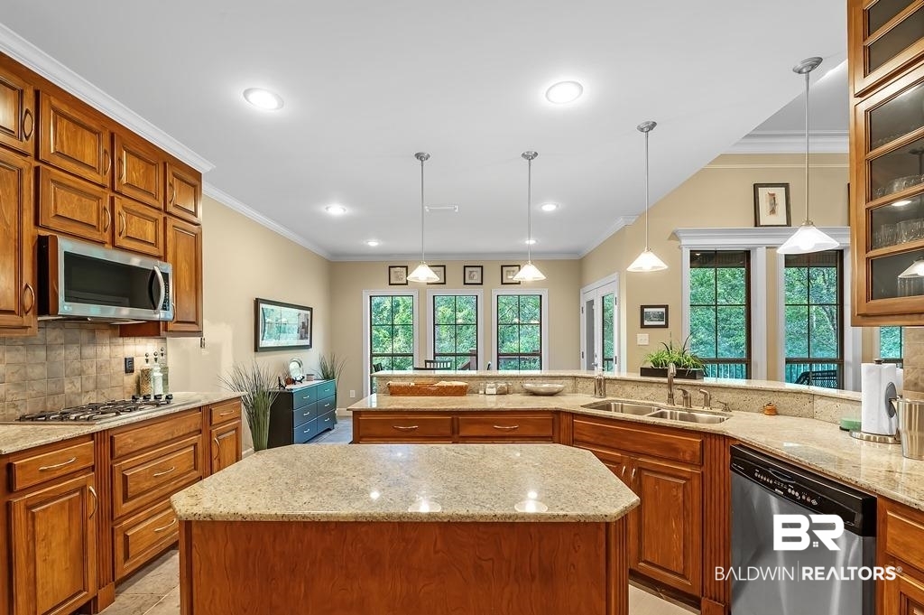 29976 Dolive Ridge Daphne, AL 36527 - Photo 25 of 58 Kitchen featuring appliances with stainless steel finishes, sink, a wealth of natural light, light stone countertops, and a center island