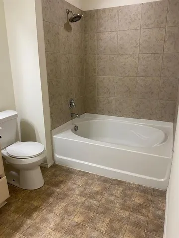 a white toilet sitting next to a bath tub