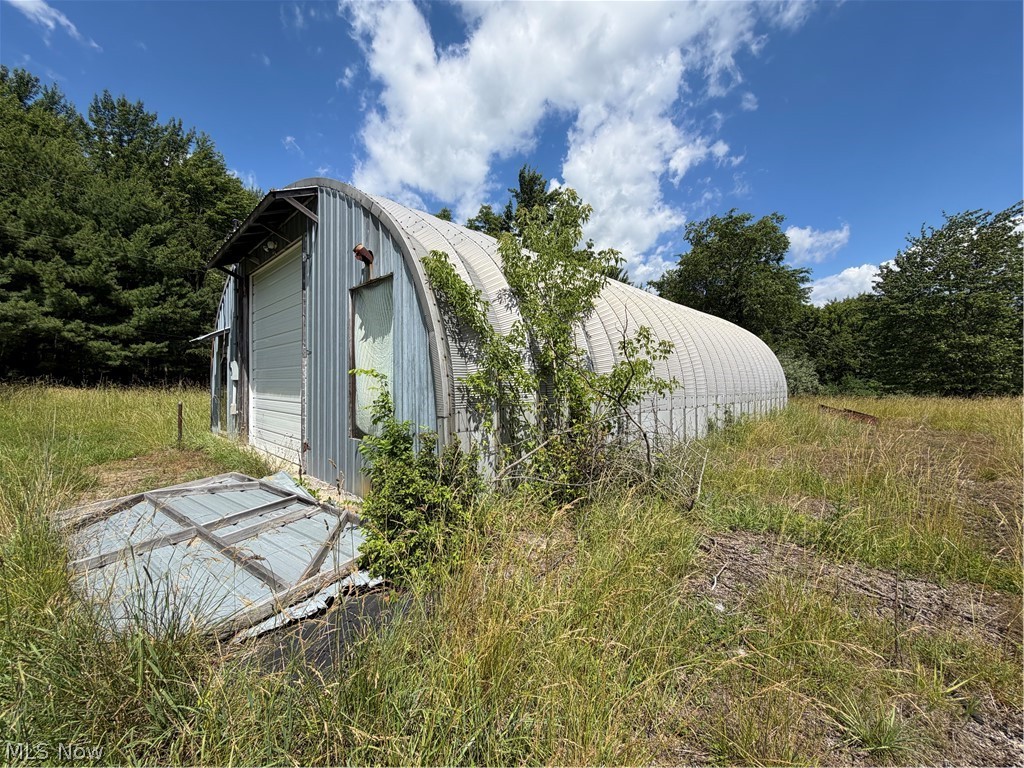 15441 Johnson Road Lisbon, OH 44432 - Photo 20 of 45 Quonset hut structure with a corrugated metal exterior, featuring a roll-up door and an entry door
