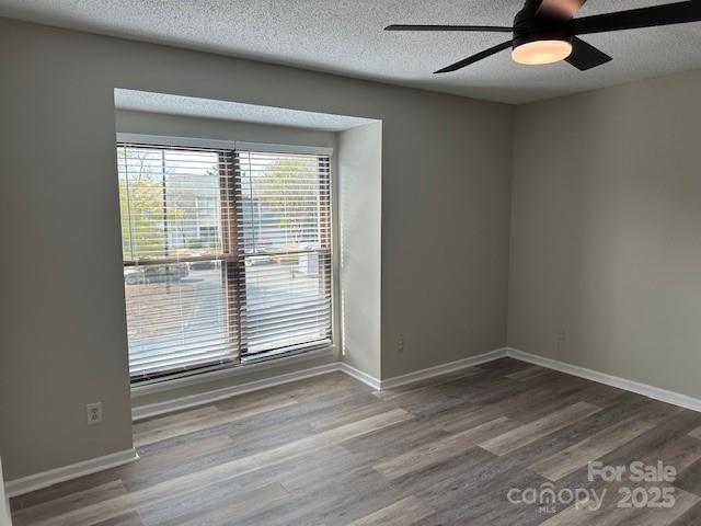 11169 Harrowfield Road Charlotte, NC 28226 - Photo 7 of 9 an empty room with wooden floor chandelier fan and windows