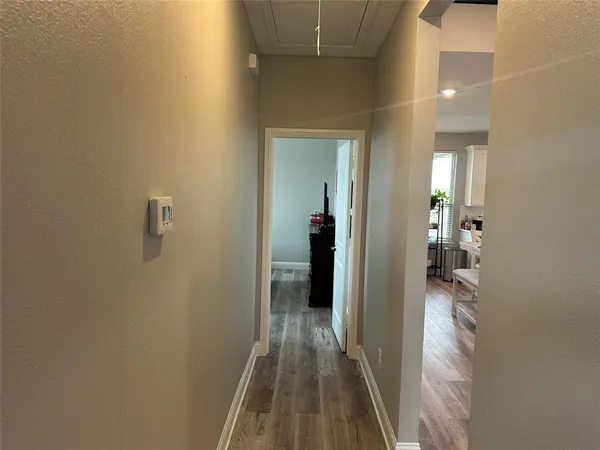 a view of a hallway with wooden floor and a bathroom