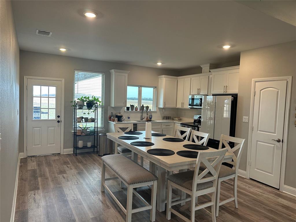 4760 County Road 4603 Commerce, TX 75428 - Photo 8 of 36 a kitchen with a dining table chairs refrigerator and cabinets