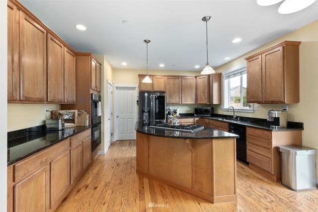 a kitchen with stainless steel appliances kitchen island granite countertop a stove a sink and a refrigerator