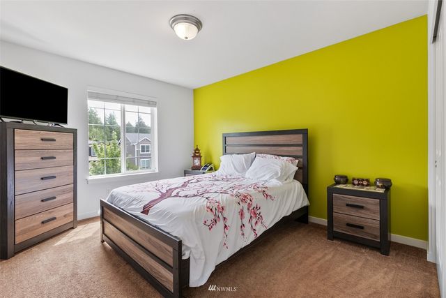 a bedroom with a bed and a flat tv screen on dresser