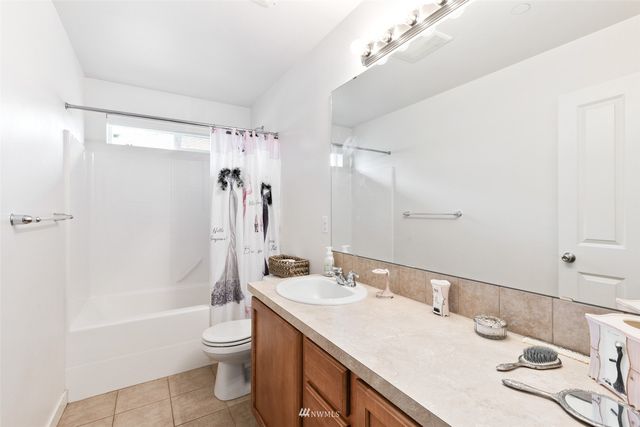 a bathroom with a granite countertop sink a toilet a mirror a bathtub and shower