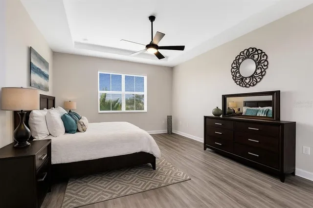 an empty room with wooden floor ceiling fan and windows