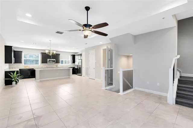 a large white kitchen with a large counter top a sink stainless steel appliances and cabinets