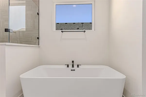 a bathroom with a tub shower and mirror