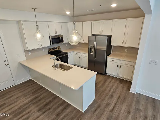 a large kitchen with stainless steel appliances a large counter top a refrigerator and a sink