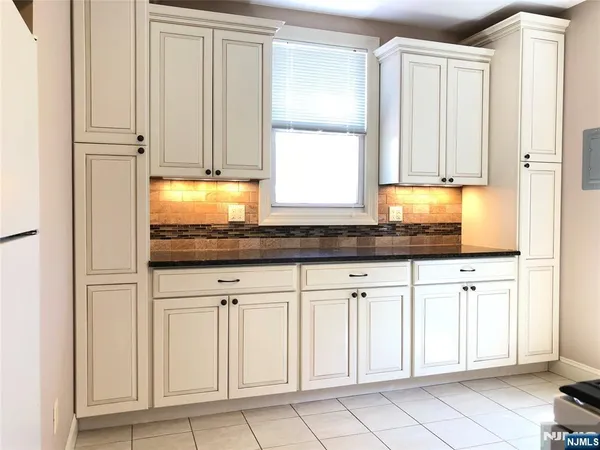 a kitchen with granite countertop white cabinets and sink