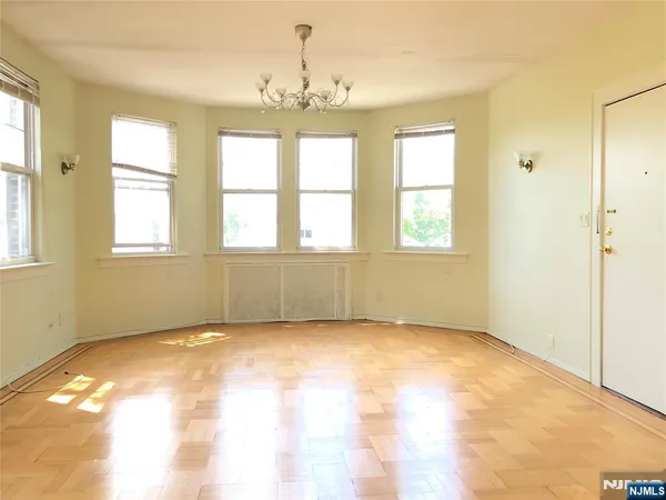 an empty room with chandelier fan and windows