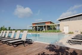 17439 Chester Valley Trail Hockley, TX 77447 - Photo 19 of 22 This photo showcases a modern home with a spacious outdoor area featuring a sleek swimming pool surrounded by lounge chairs. The house has a contemporary design with large windows, offering a bright and open feel. Perfect for relaxation and entertainment.