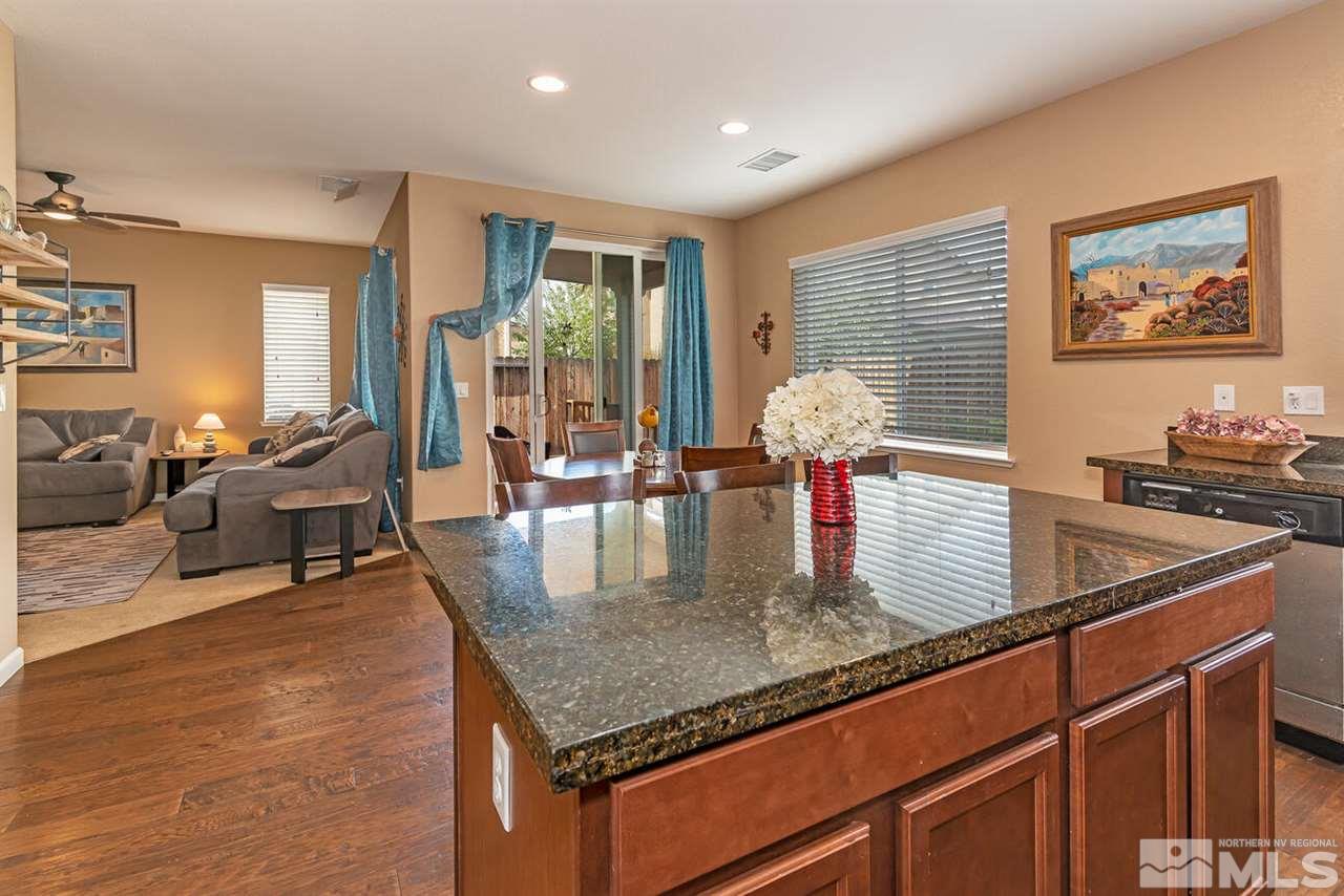 2065 Bears Ranch Drive Reno, NV 89521 - Photo 5 of 20 a kitchen with stainless steel appliances granite countertop a stove top oven a dining table and chairs with wooden floor