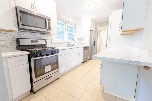 a kitchen with stainless steel appliances white cabinets and a stove top oven
