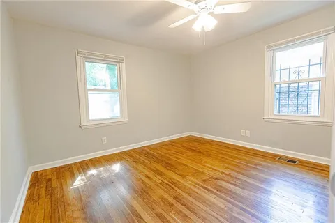a view of empty room with wooden floor and fan
