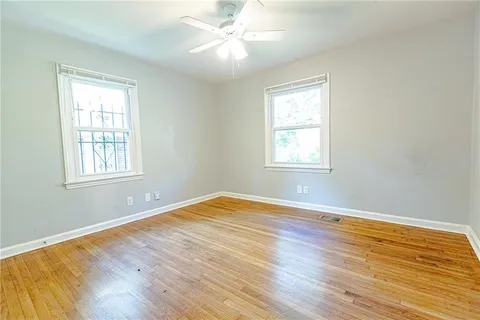 a view of an empty room with wooden floor and window