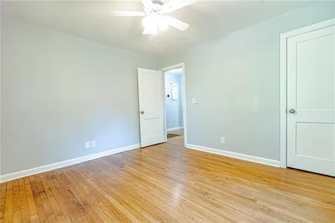 an empty room with wooden floor and fan