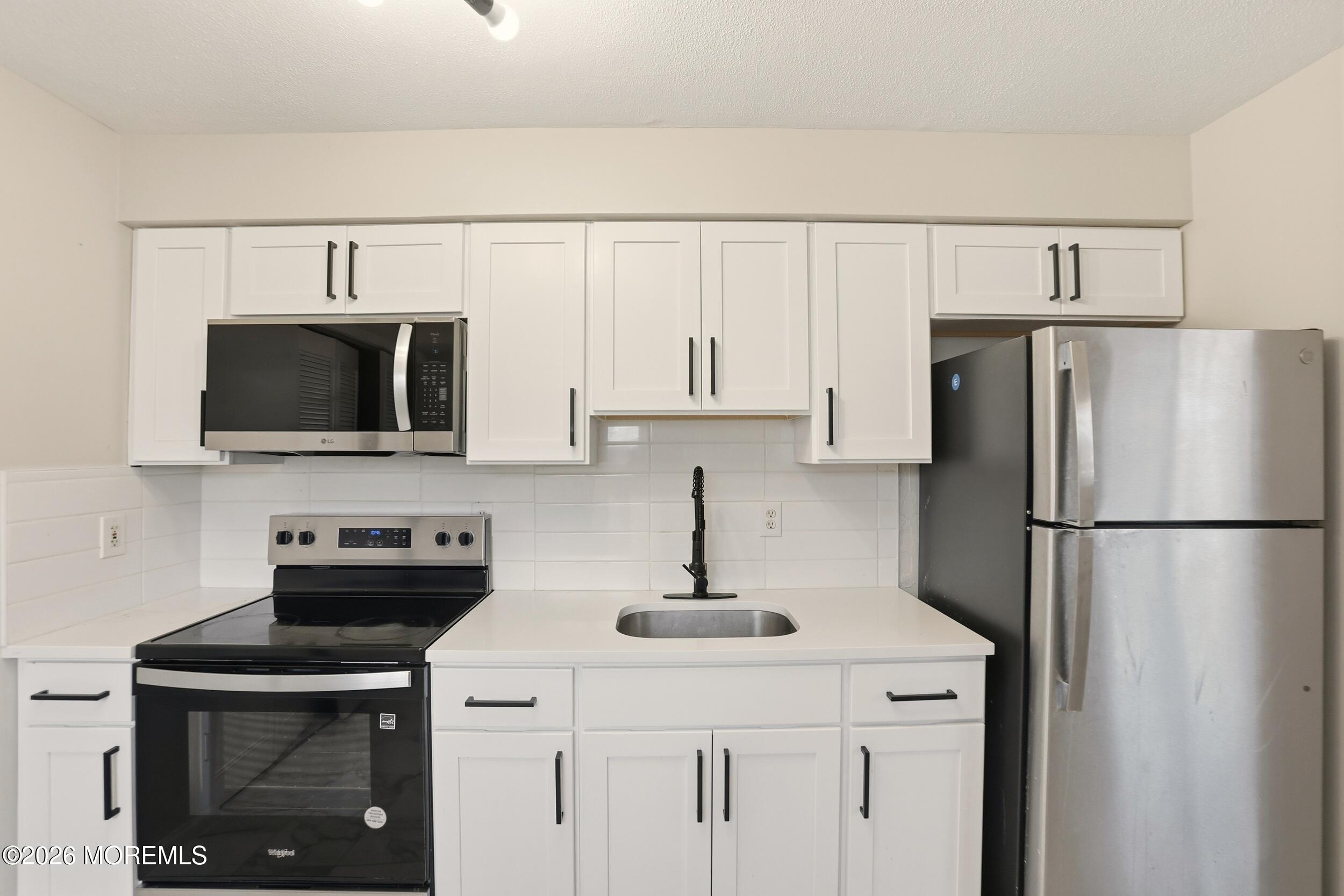 194 Sawmill Road, Unit 480 Brick, NJ 08724 - Photo 18 of 20 a kitchen with refrigerator a microwave a sink and cabinets