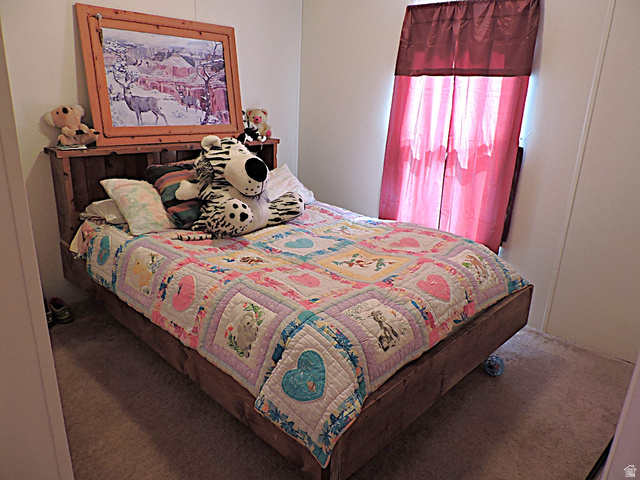 915 North 5000 W Road Hinckley, UT 84635 - Photo 16 of 27 Bedroom featuring light-toned walls, a window with red privacy curtains, and carpeting