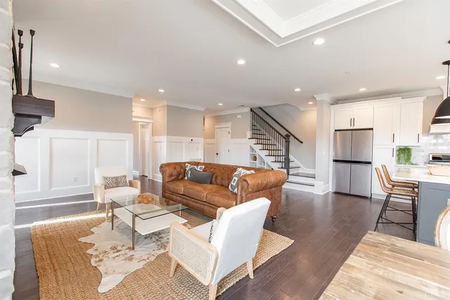 a kitchen with stainless steel appliances granite countertop a stove a sink a oven and a large window with wooden floors