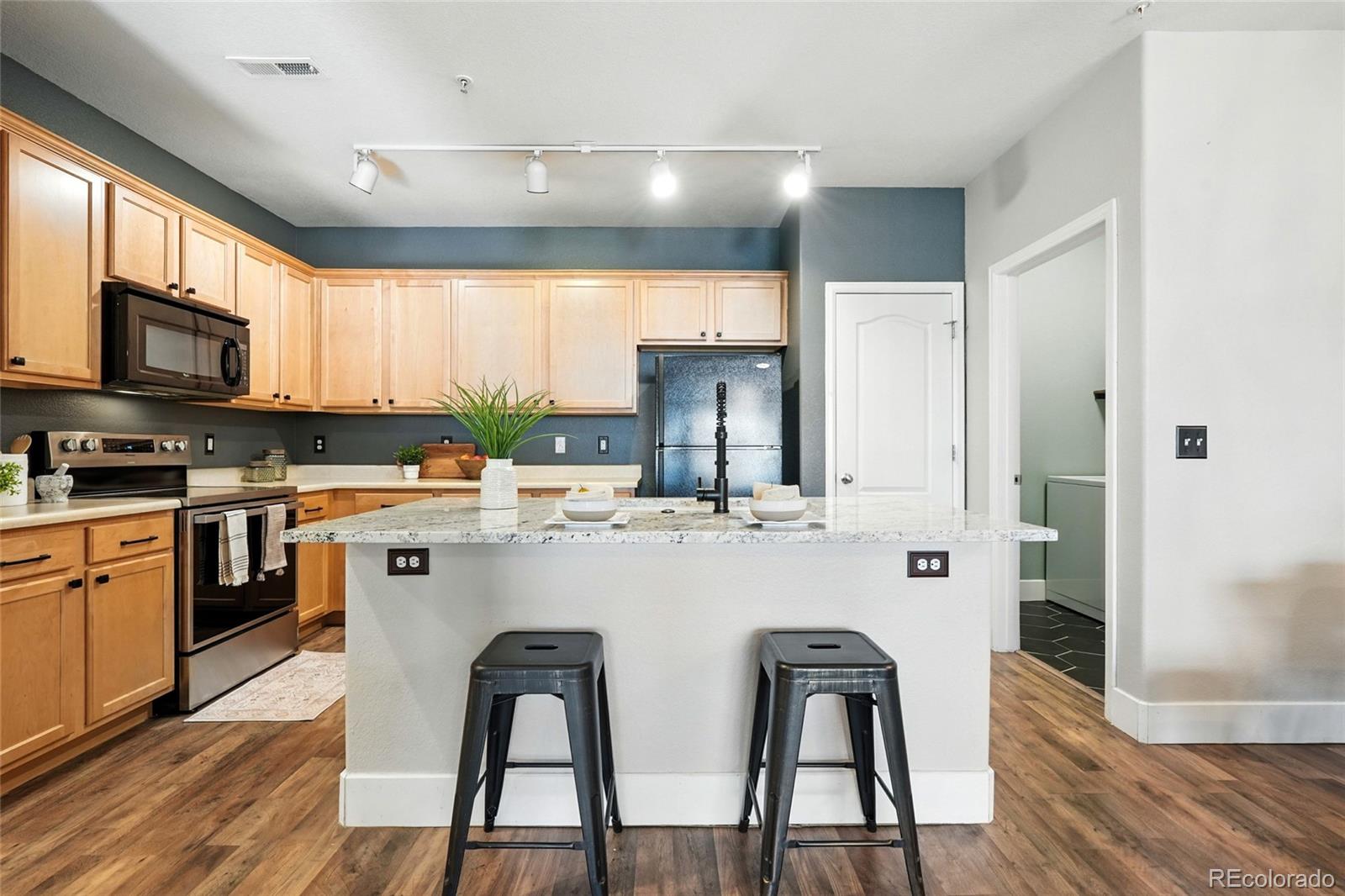 7080 Simms Street, Unit 204 Arvada, CO 80004 - Photo 15 of 49 a kitchen with stainless steel appliances granite countertop a stove top oven a sink a dining table and chairs with wooden floor