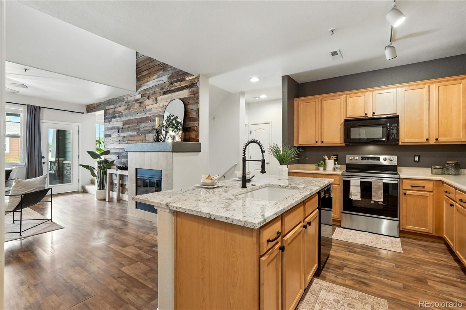 7080 Simms Street, Unit 204 Arvada, CO 80004 - Photo 18 of 49 a kitchen with stainless steel appliances granite countertop a stove top oven a sink dishwasher a dining table and chairs with wooden floor