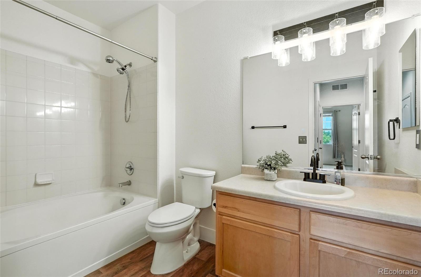 7080 Simms Street, Unit 204 Arvada, CO 80004 - Photo 25 of 49 a bathroom with a sink a toilet a mirror a bathtub and shower