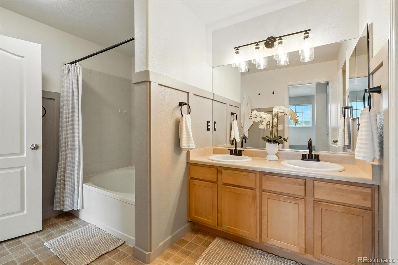 7080 Simms Street, Unit 204 Arvada, CO 80004 - Photo 33 of 49 a bathroom with a double vanity sink mirror and shower
