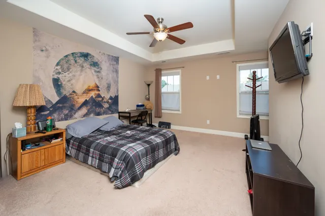 a spacious bedroom with a bed and a flat tv screen on the dresser