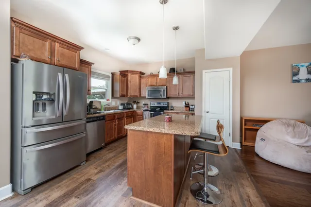 a kitchen with stainless steel appliances granite countertop a refrigerator a stove and a sink with wooden floor