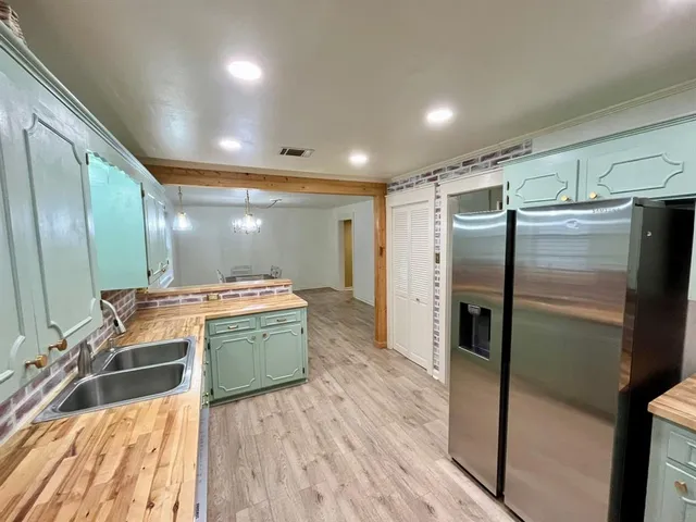 a kitchen with kitchen island a counter top space a sink a refrigerator and a stove