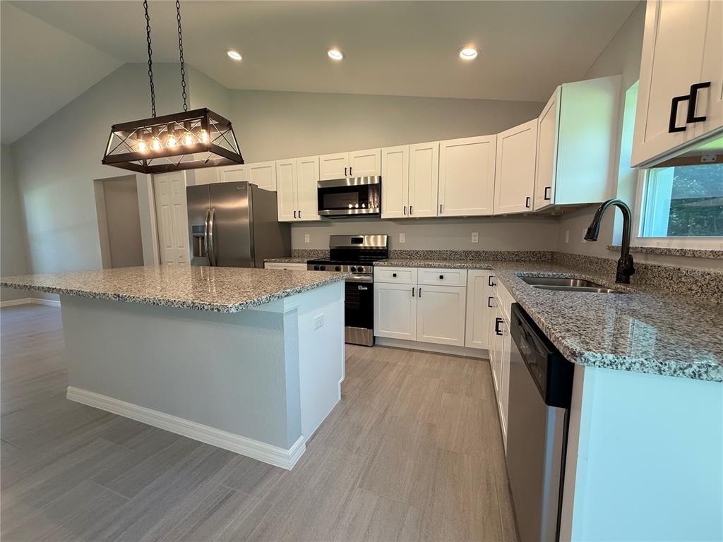 205 Emerald Road Ocala, FL 34472 - Photo 2 of 18 a kitchen with granite countertop stainless steel appliances a stove sink microwave and cabinets