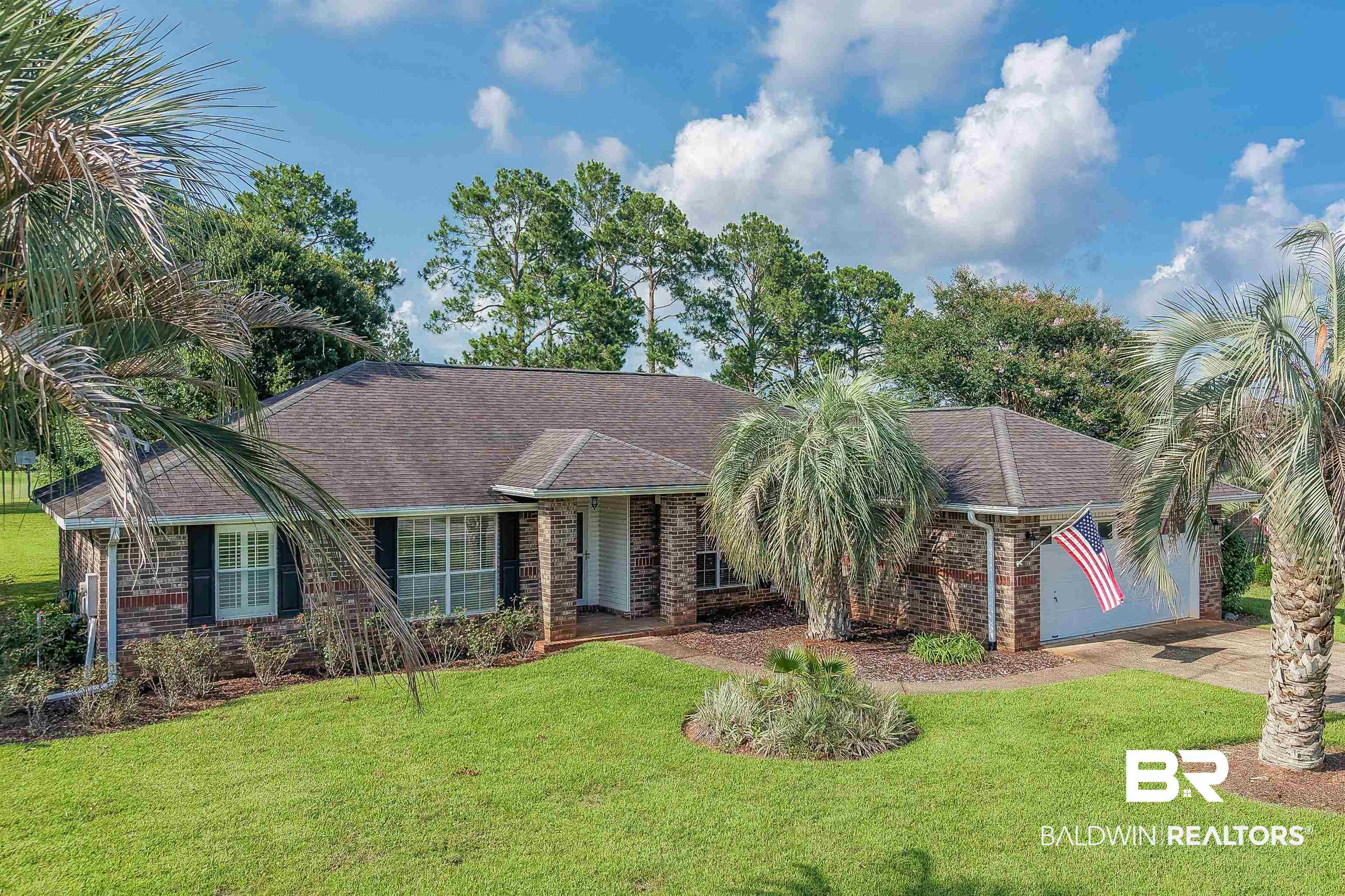 22685 County Road 12 Foley, AL 36535 - Photo 1 of 89 Brick exterior with dark shutters, established landscaping, prominent palm trees, and an attached two-car garage