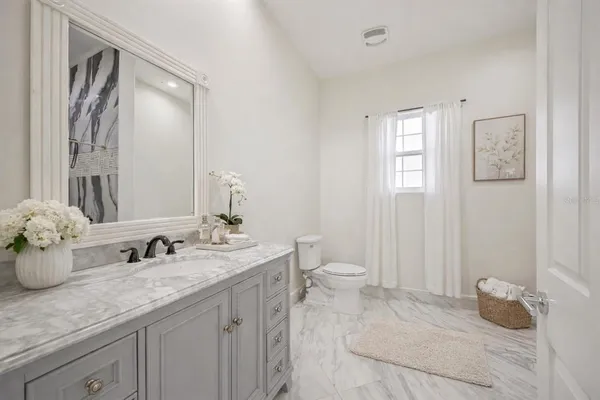 a bathroom with a granite countertop sink mirror and toilet