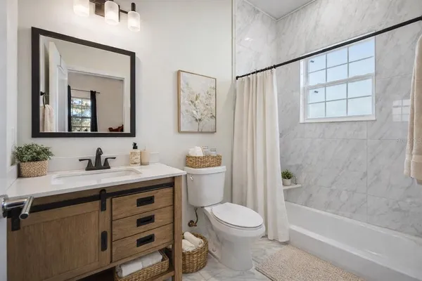 a bathroom with a granite countertop sink toilet a large mirror a shower and a bathtub
