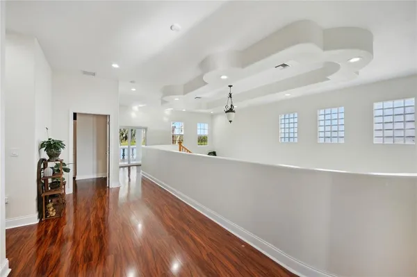 a living room with stainless steel appliances furniture a refrigerator and a wooden floor