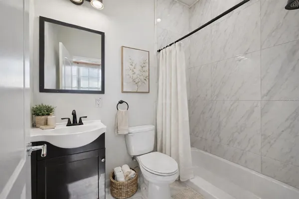a bathroom with a toilet sink vanity tub and mirror
