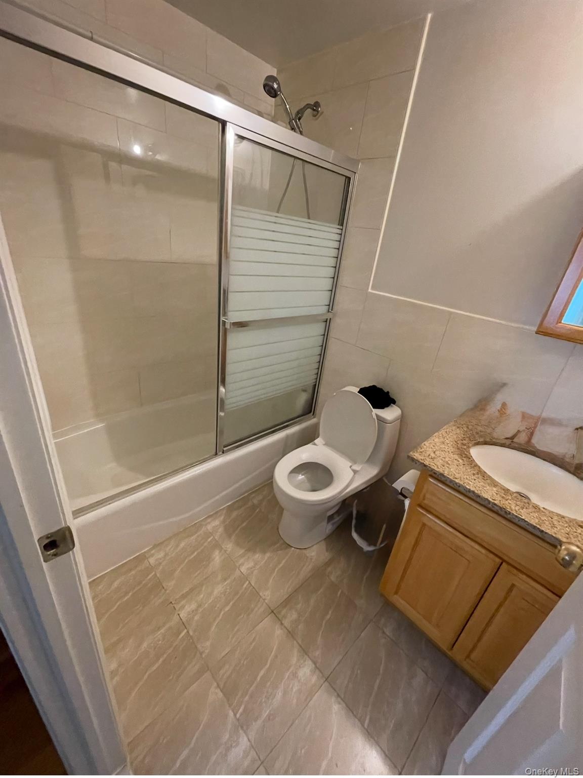 137-08 31st Road, Unit 5D Queens, NY 11354 - Photo 2 of 4 Bathroom featuring vanity, bath / shower combo with glass door, and tile walls