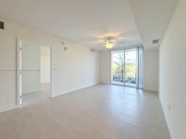 an empty room with windows and chandelier fan