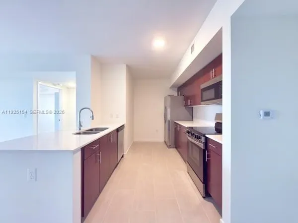 a large kitchen with stainless steel appliances a sink and cabinets