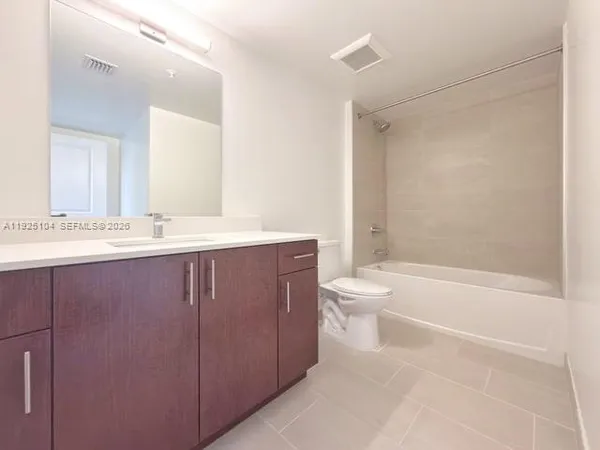 a bathroom with a bathtub shower sink vanity mirror and toilet